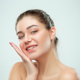 The beautiful female face. The perfect and clean skin of face on gray