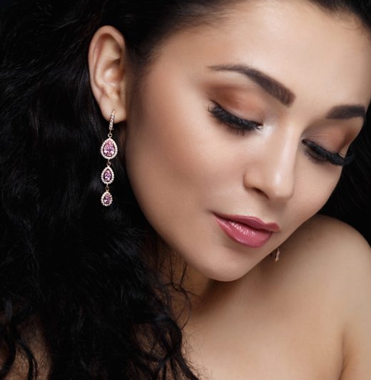 Long earring with violet precious stones hang from woman's ear
